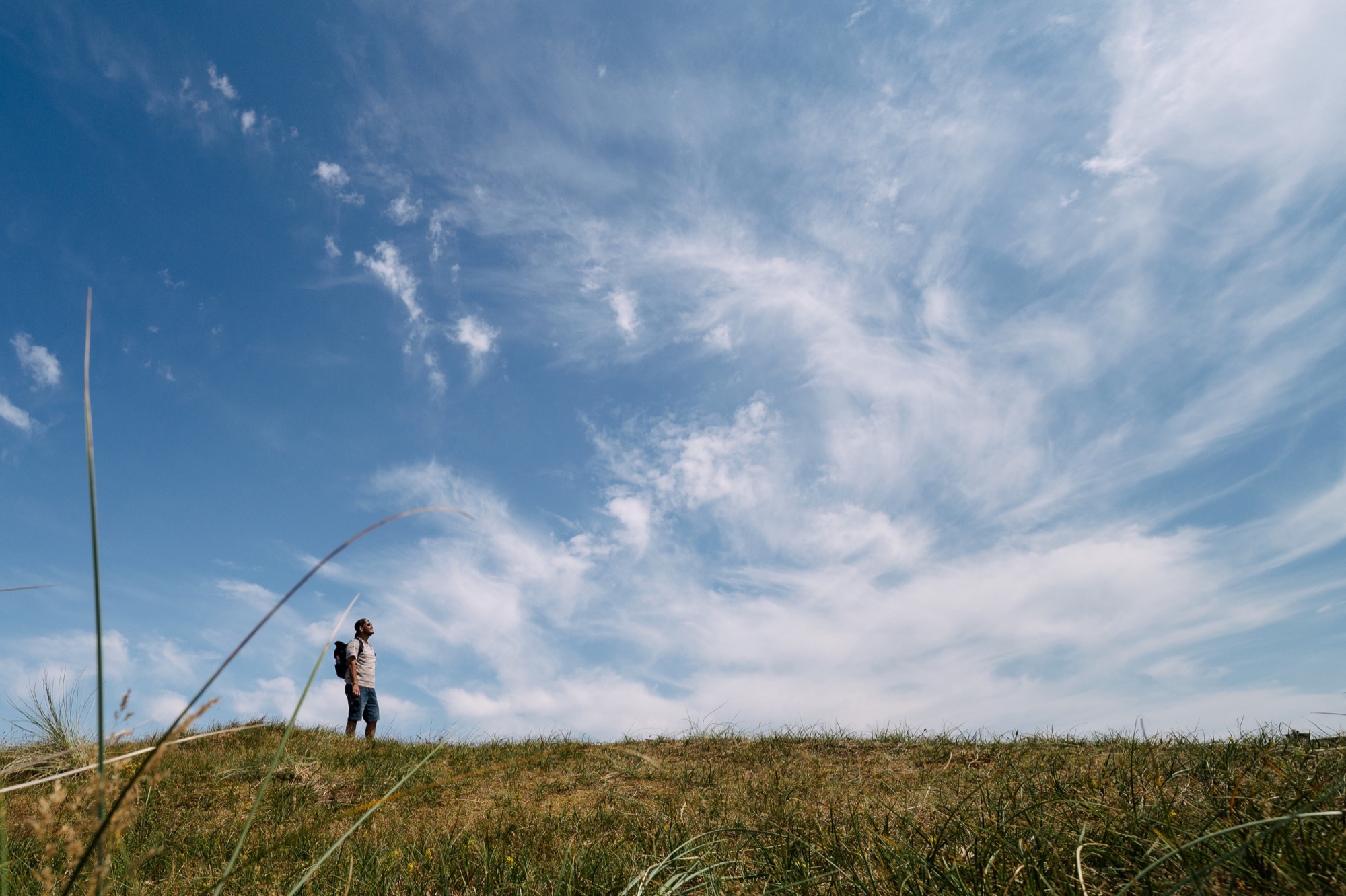 Persoon loopt door de duinen onder een wolkenlucht