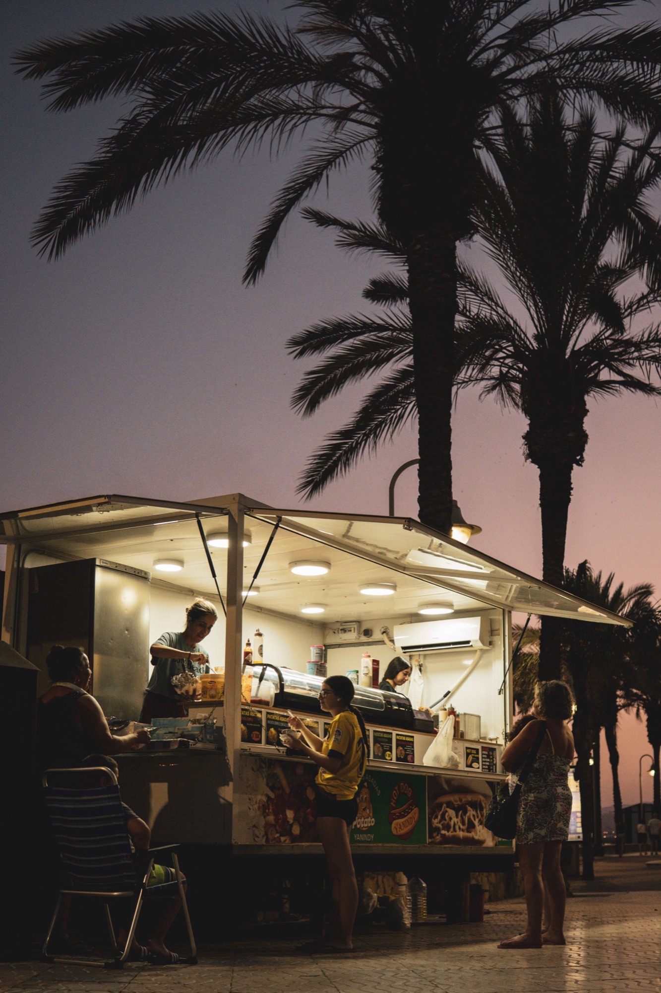 Foodtruck onder palmbomen in de schemering